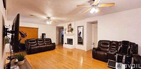 A living room with a black leather couch and a television.