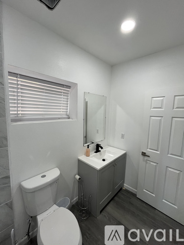 A bathroom with a toilet, sink, and mirror.