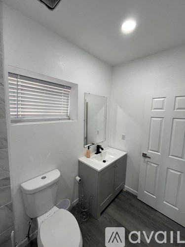 A bathroom with a toilet, sink, and mirror.