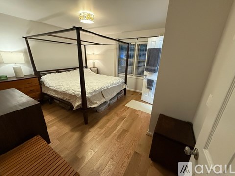 A bedroom with a four poster bed and wooden flooring.