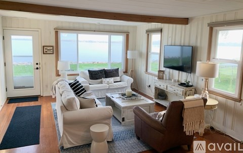 A living room with a white couch, a brown chair, and a television on a white stand.