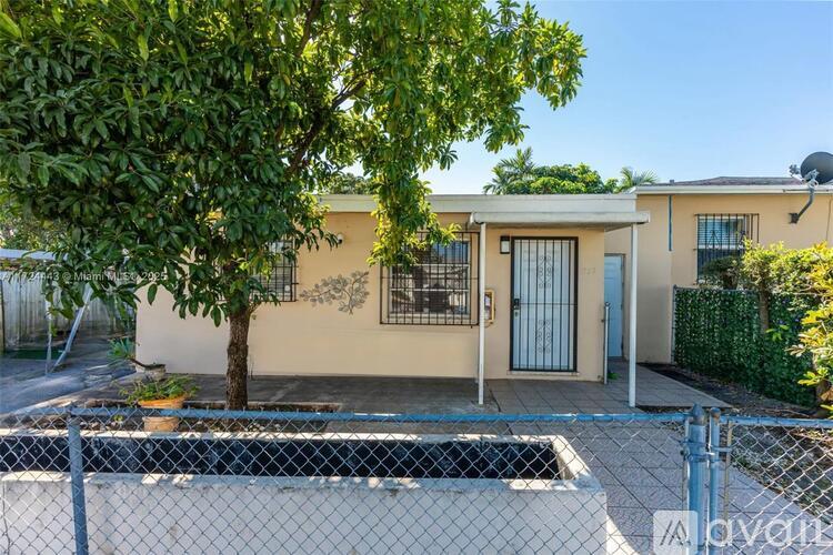 A house with a fence and a tree in front of it.