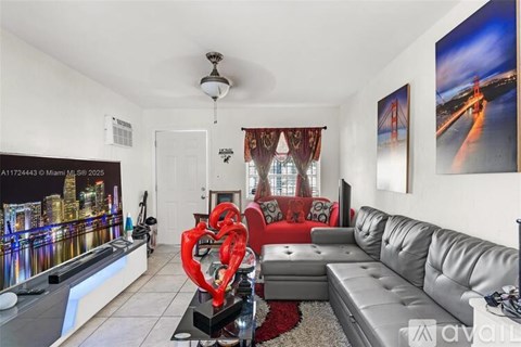 A living room with a grey sofa and a red heart-shaped object on a black stand.