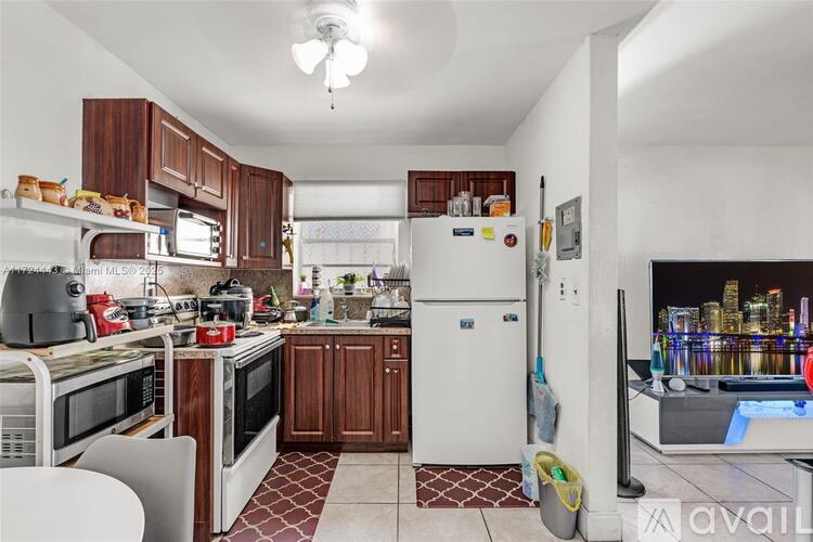 A kitchen with a refrigerator, microwave, and oven.