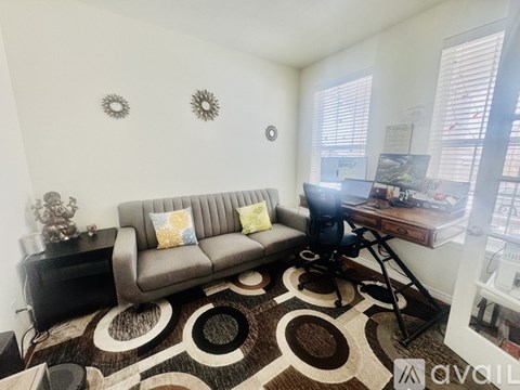 A living room with a grey couch and a patterned rug.