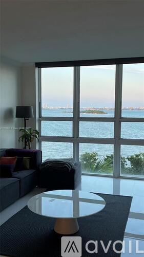 A living room with a glass table and a view of the water.