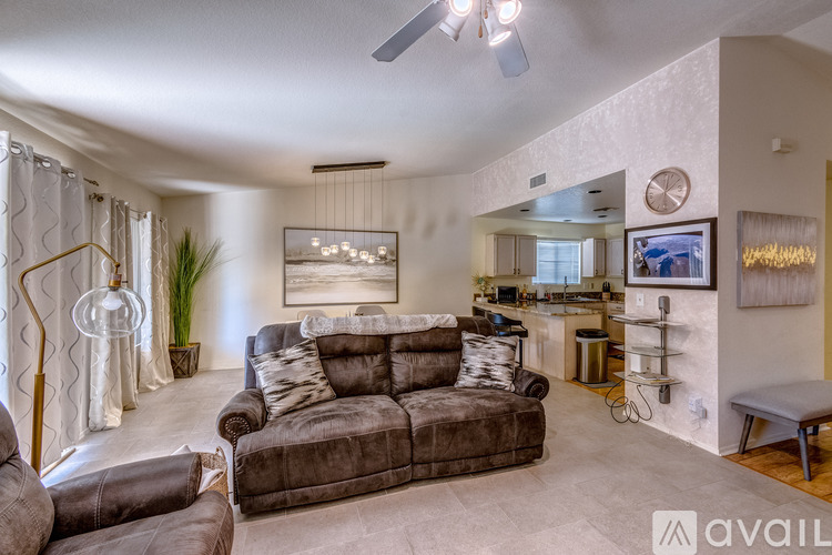 A living room with a grey couch and a painting on the wall.