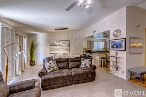 A living room with a grey couch and a painting on the wall.