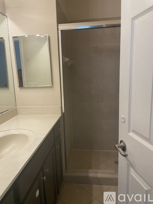 A bathroom with a sink, mirror, and shower.