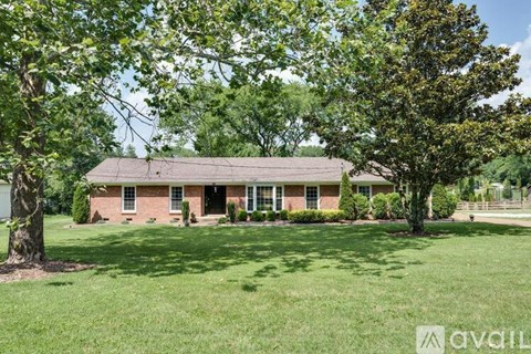 A house with a lawn and trees in front of it.