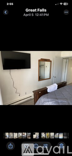 A bedroom with a bed, mirror, and a flat screen TV mounted on the wall.