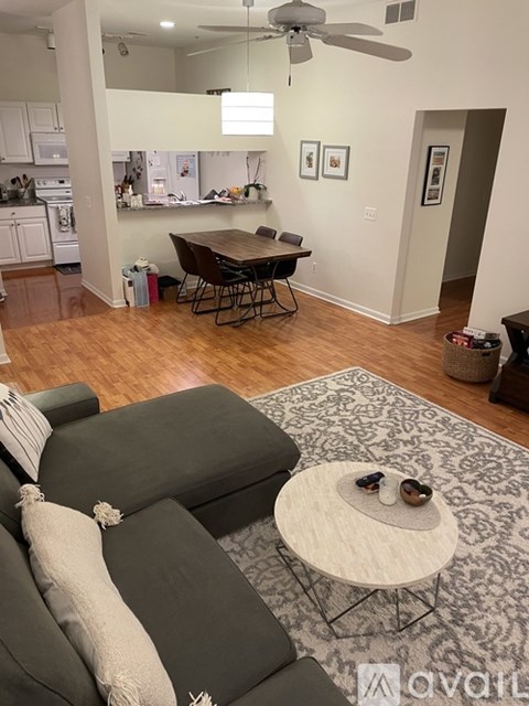 A living room with a grey couch and a round table with a small dog on it.