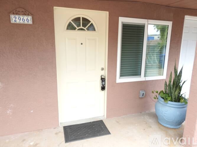 A white door with a glass window above it and a blue pot to the right.