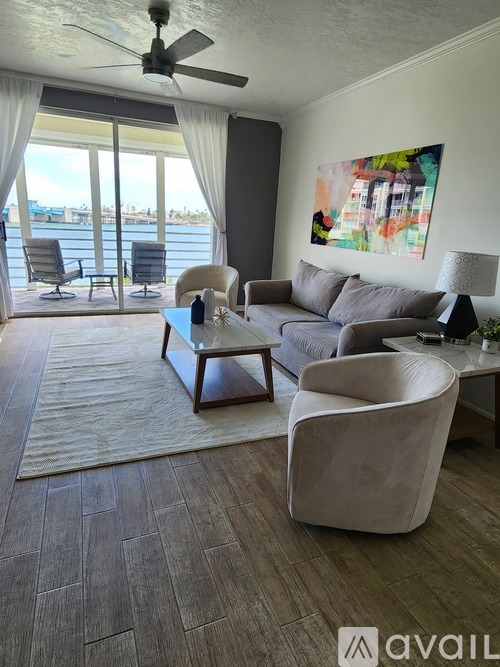 A living room with a grey couch, a white chair, and a painting on the wall.