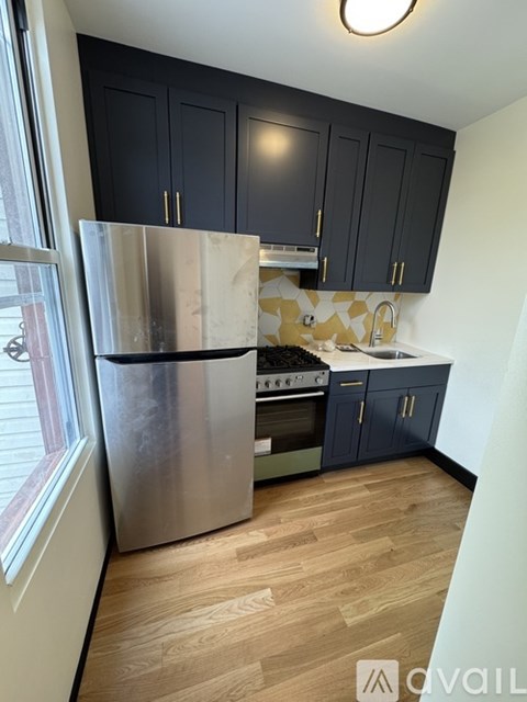 A kitchen with a stainless steel refrigerator and wooden flooring.