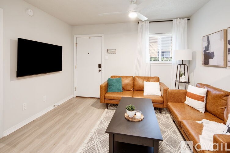 A living room with a brown leather couch and a black TV mounted on the wall.