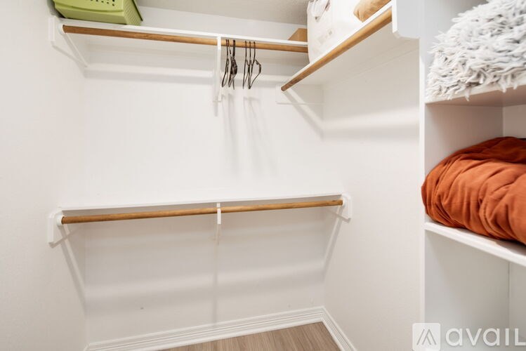 A white closet with two shelves and a bed.