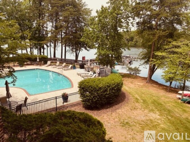 A pool surrounded by greenery and a view of the water.