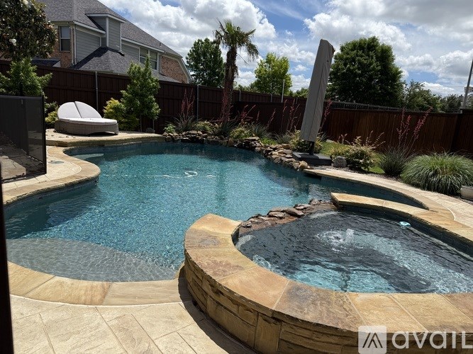 A hot tub sits in the middle of a pool surrounded by a stone patio.