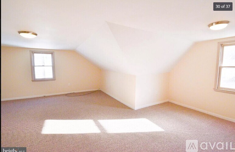 A room with a window and a carpeted floor is available for rent.