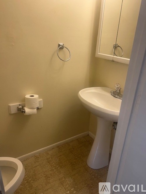 A bathroom with a toilet, sink, and mirror.