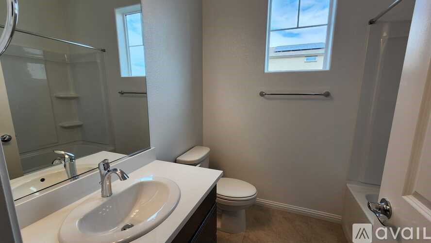 A bathroom with a sink, toilet, and a window.