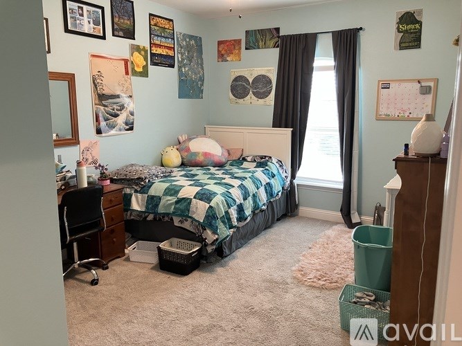 A bedroom with a bed, desk, chair, and pictures on the wall.