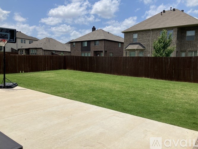 A backyard with a basketball hoop and a fence.