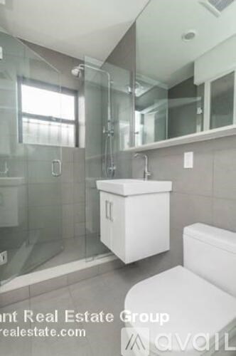 A white toilet sits in a modern bathroom with a walk-in shower.