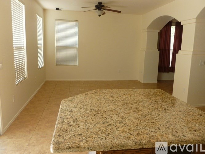 A room with a fan, windows, and a bed in it.