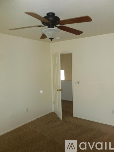 A room with a ceiling fan and a door.