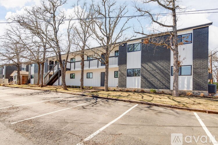 A parking lot in front of a multi-story building with trees.