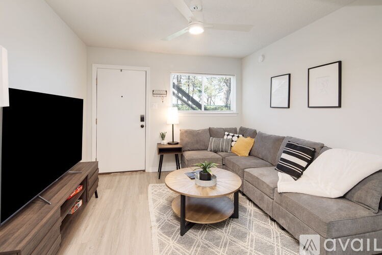 A living room with a grey couch, a coffee table, and a flat screen TV.