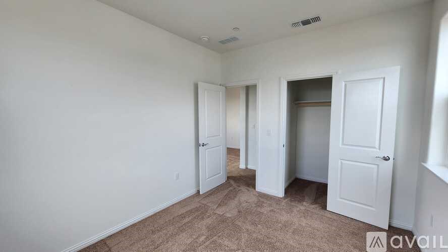 A room with white walls and a carpeted floor with four doors.