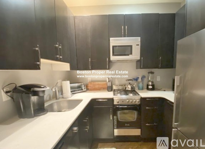 A kitchen with black cabinets and stainless steel appliances is on the market.