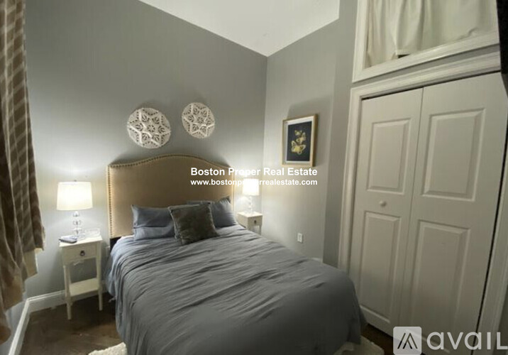 A bedroom with a large bed and a lamp on a nightstand.