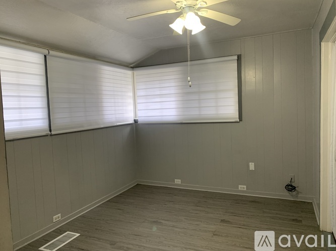 A room with a ceiling fan and wooden flooring.
