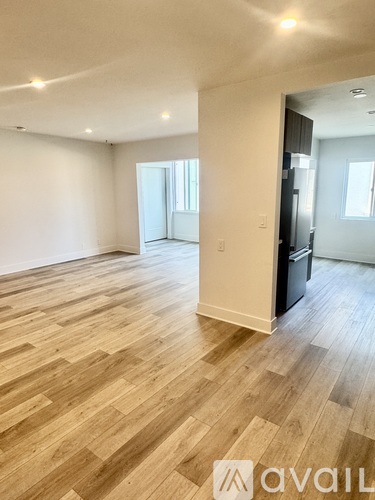 A spacious room with wooden flooring and white walls.