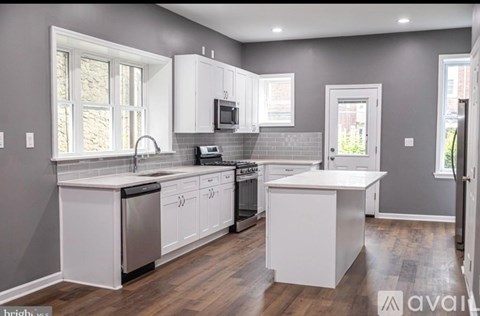 A kitchen with white cabinets and a wooden floor.