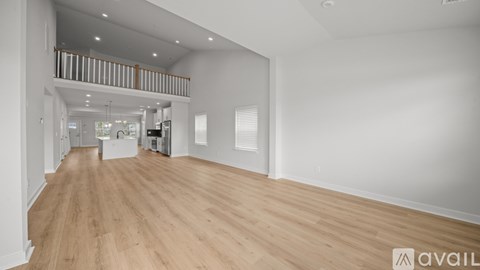 A spacious room with wooden flooring and white walls.