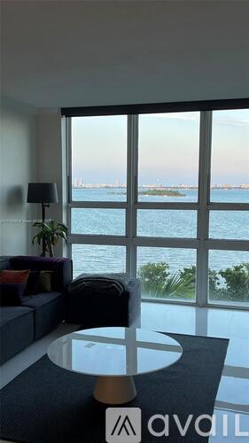 A living room with a glass table and a view of the water.