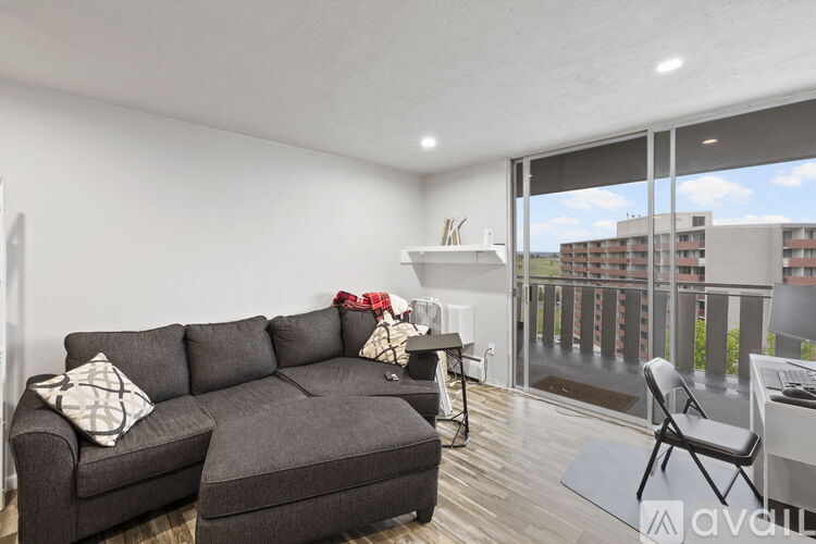 A living room with a grey couch and a chair with a view of a building outside.