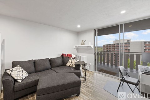 A living room with a grey couch and a chair with a view of a building outside.
