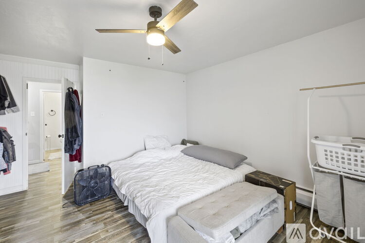 A bedroom with a bed, a ceiling fan, and a laundry basket.