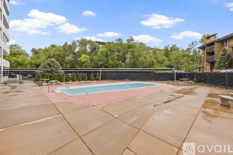 A pool surrounded by a black fence and trees.