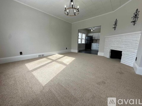 A spacious living room with a fireplace and a chandelier.
