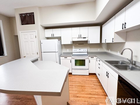 A kitchen with white cabinets and a white island.