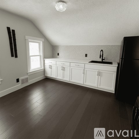 A kitchen with white cabinets and a black refrigerator.