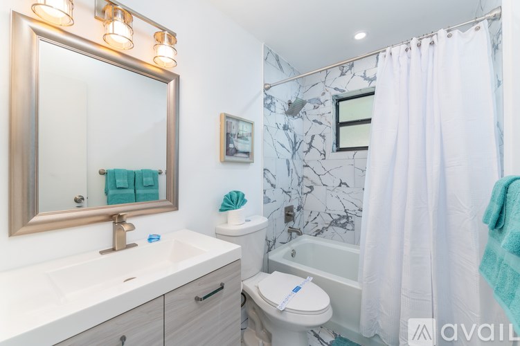 A bathroom with a white sink, toilet, and shower curtain.