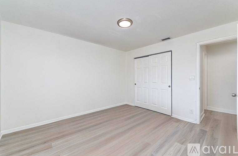 A room with a white door and wooden flooring.